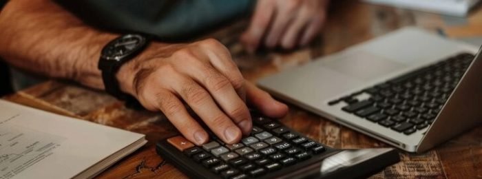 Person using a financial calculator, planning their savings and investments Person using a financial calculator, planning their savings and investments